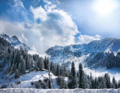 Зимняя долина снежных гор с туманом и солнцем в Чумбулаке, Алматы, Казахстан